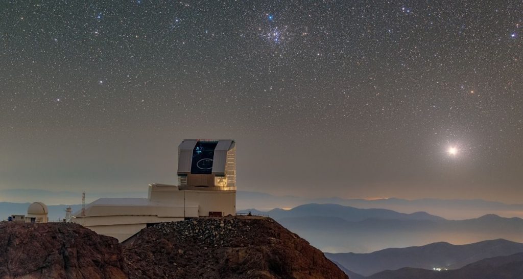 El Observatorio Vera C. Rubin de la NSF–DOE se ve con su cúpula abierta durante las actividades de observación First Look en abril de 2025. M41, el cúmulo Little Beehive, se puede ver sobre el telescopio. Créditos: RubinObs/NOIRLab/SLAC/NSF/DOE/AURA/P. Horálek (Institute of Physics in Opava)