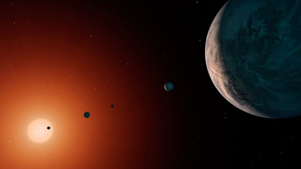 El exoplaneta TRAPPIST-1e, uno de los siete mundos del sistema TRAPPIST-1, vuelve a cobrar protagonismo gracias a nuevas observaciones del Telescopio Espacial James Webb. Situado en la zona habitable de su estrella, este planeta podría albergar agua líquida si posee una atmósfera estable. Los últimos estudios publicados en Astrophysical Journal Letters analizan posibles señales de metano, aunque los científicos advierten que podrían proceder de la propia enana roja. La comunidad científica continúa investigando para determinar si TRAPPIST-1e es realmente un candidato a albergar condiciones aptas para la vida.